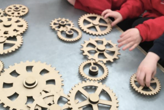 Children playing with some wooden cogs.