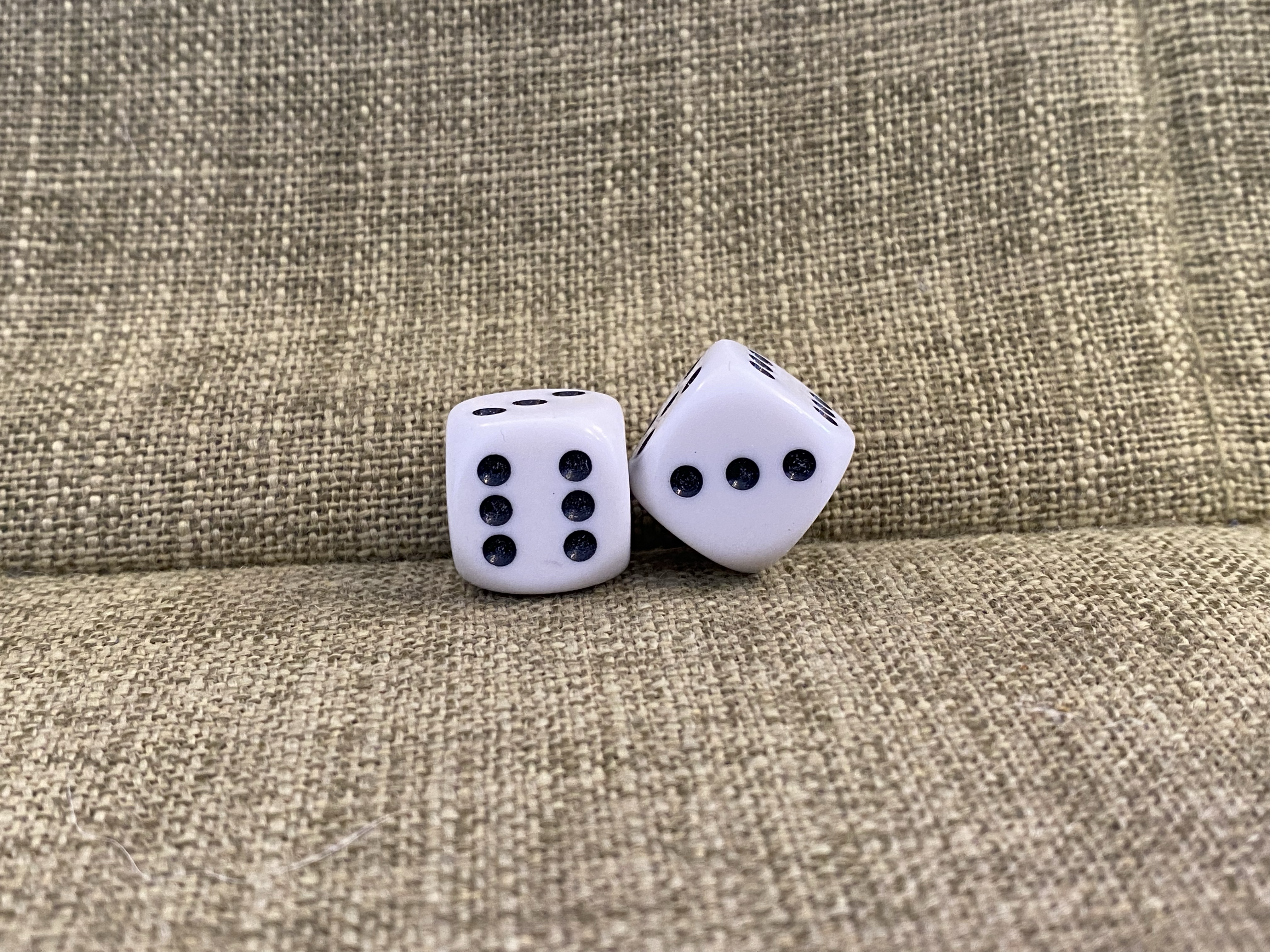 Two dice showing a 6 and a 3 on a pale green background.
