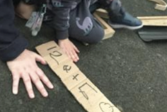 A ruler made by a child being used to measure a hand.